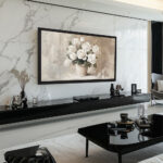 A striking 75-inch framed TV displaying white roses against a marble wall, using the bold black oak finish to create a sophisticated, high-contrast focal point in a modern living room.