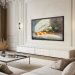 A beautiful 50-inch framed TV displaying classic still life art in an elegant, bright living room, showing how the black oak frame provides a sophisticated anchor for light-toned spaces.