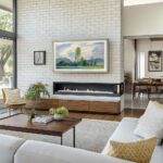 A 75-inch framed TV displaying landscape art in a bright, mid-century modern living room, seamlessly blending your large entertainment system into your home's sophisticated architecture.