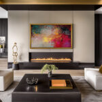 A stunning 85-inch framed TV displaying vibrant abstract art above a modern fireplace, instantly elevating a sleek luxury living room by hiding the blank black screen.