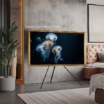 An ornate gold framed TV mounted on a stylish easel stand in a contemporary bedroom, showcasing how this versatile frame easily accommodates freestanding setups to elevate your decor.