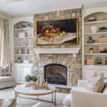 A gorgeous 75-inch framed TV displaying a classic still life above a rustic stone fireplace, beautifully blending your modern entertainment system into cozy, traditional home architecture.