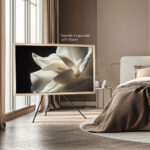 A 50-inch Samsung The Frame TV enhanced with a custom silver frame and mounted on a tripod studio stand, highlighting the frame's secure fit and versatility for freestanding room layouts.