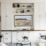 A 55-inch television upgraded with a custom wood TV frame, seamlessly integrated into white built-in cabinetry. Beautifully turns a large, blank screen into a sophisticated decorative focal point.