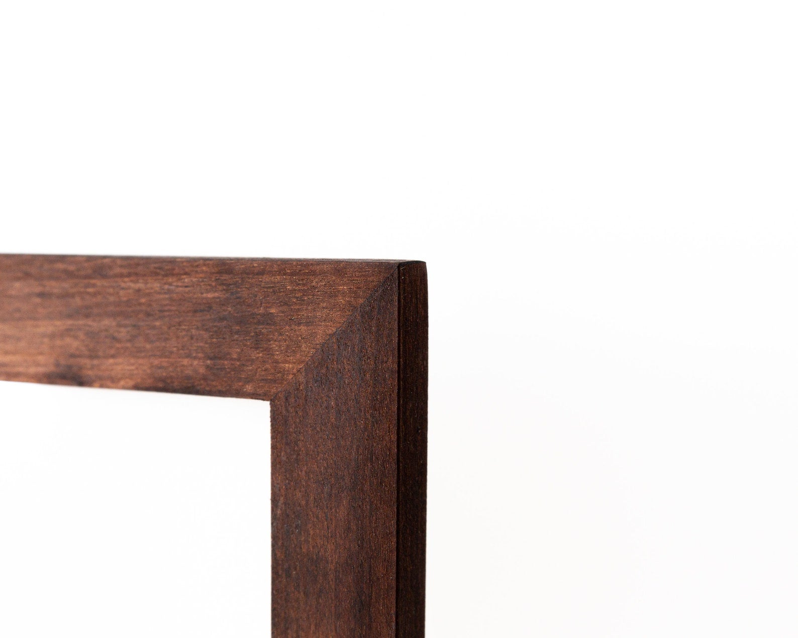 Close-up of a wooden frame corner on a white background. Custom wooden picture frame, birch hardwood, brown walnut color, handmade quality, custom sizes A4, A5, A3, 8x10, 5x7, 20x30, 14x18, 22x28
