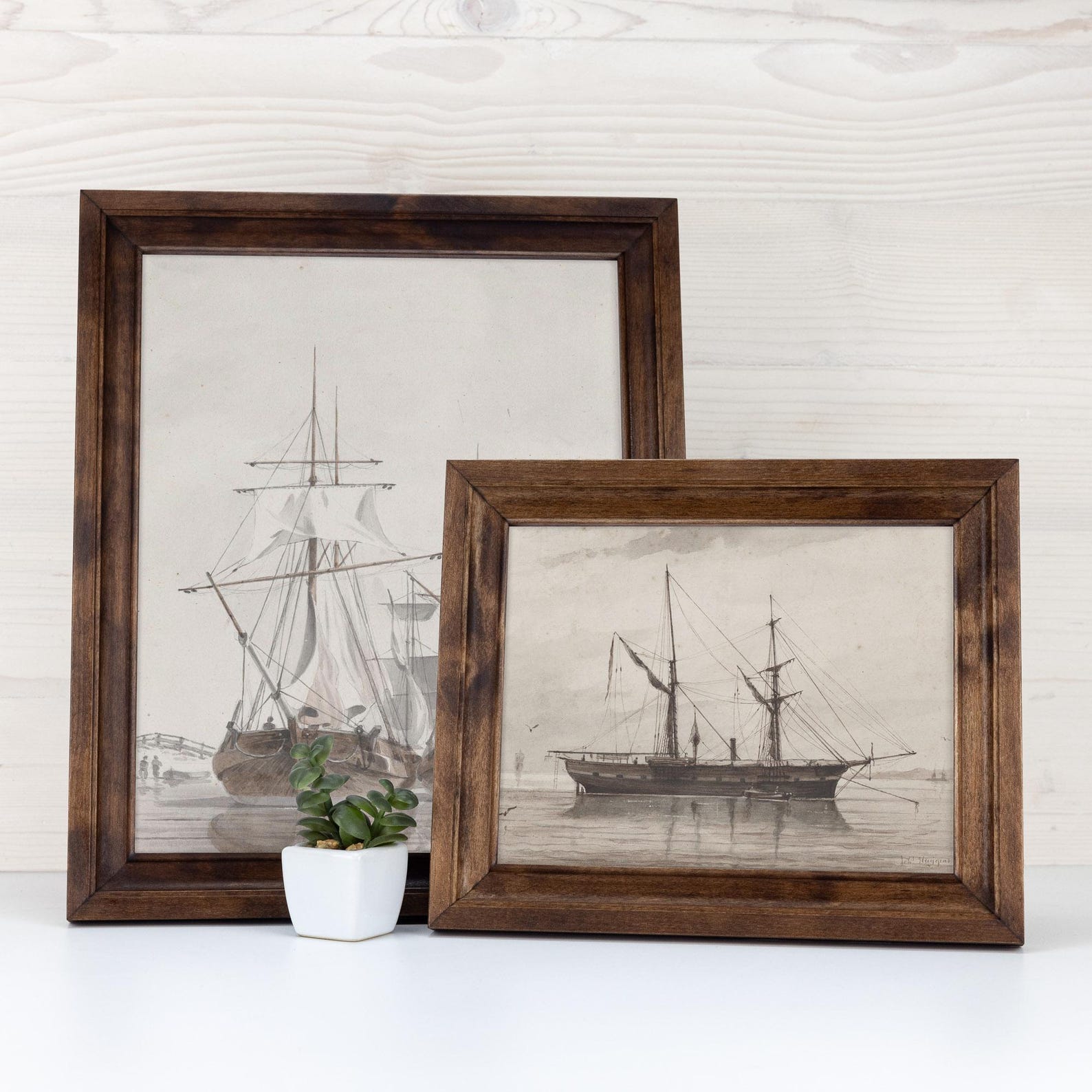 Two framed black and white ship illustrations on a white surface with a white brick wall background. Handmade Walnut Brown Picture Frame, Rustic Custom Photo Frame, Museum Quality Birch Hardwood Frame A1 A4 8x8 12x12 14x20 20x30 36x40