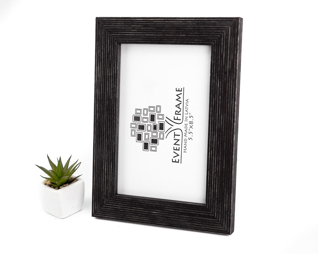 A black solid birch hardwood picture frame with a unique stripy design, displayed with a small potted plant to the side.