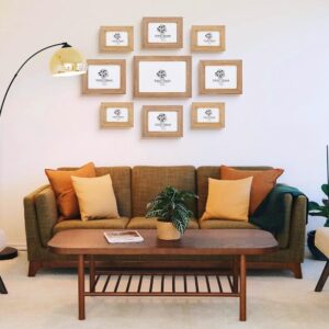 Set of natural wood handrafted quality picture frames in modern home on blank wall above couch.