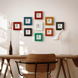 Colorful handmade wooden picture frame set for square photos above a desk in natural home office environment.